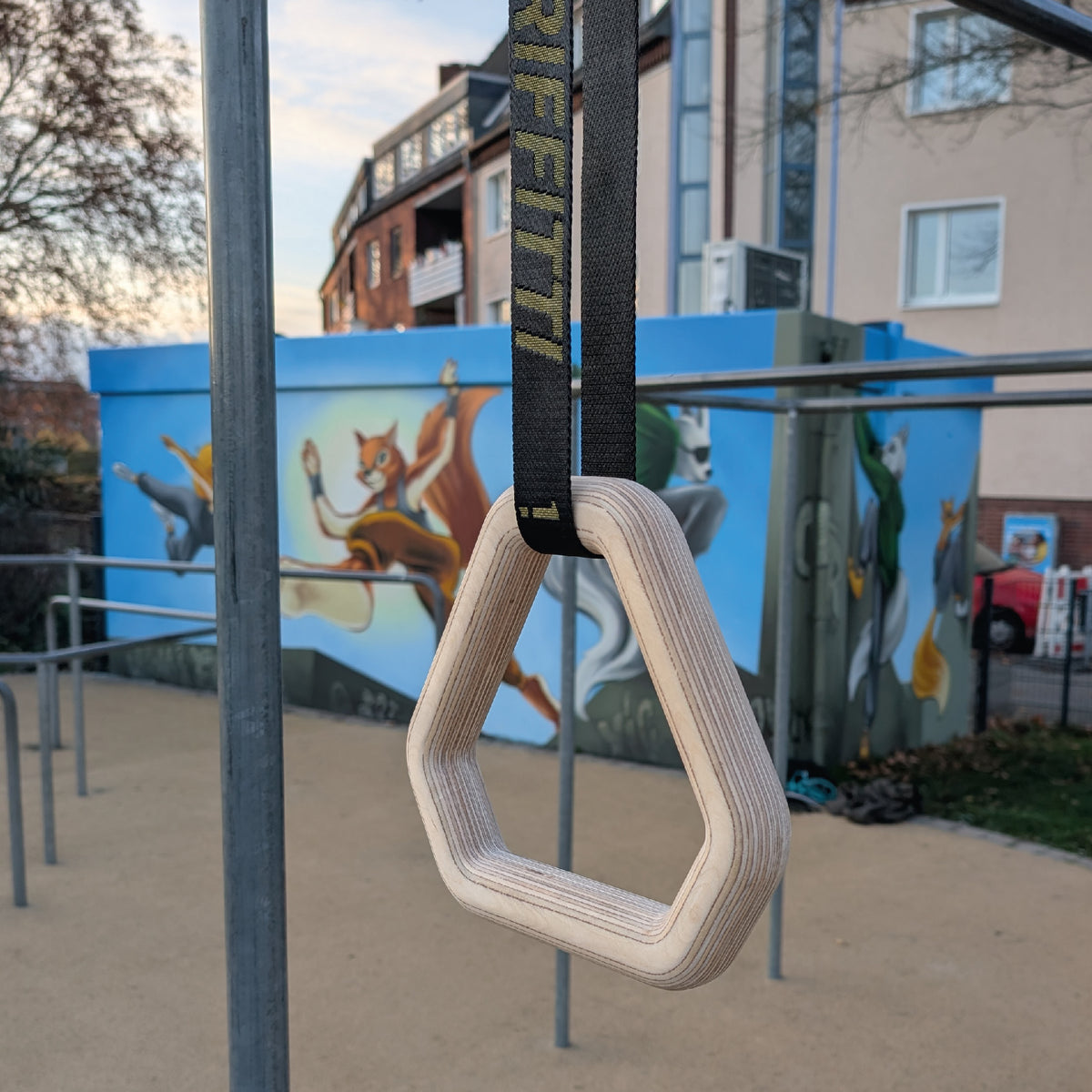 Triangel-Turnring aus Holz an einer Stange im Outdoor-Calisthenics-Park
